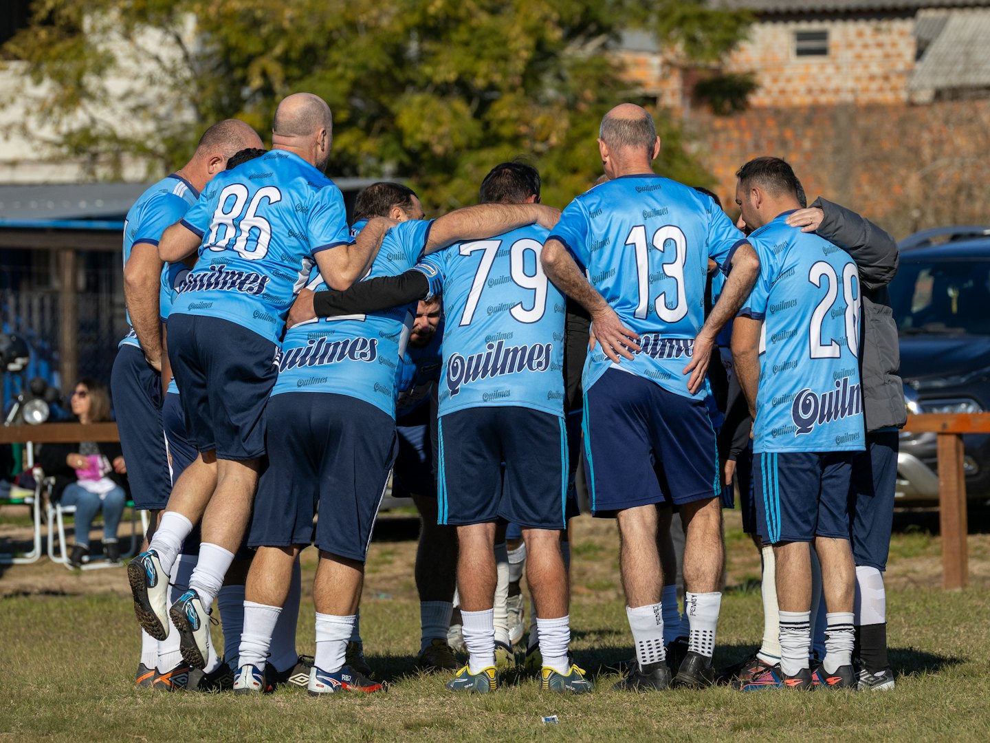 Sportteam in blauen Trikots steht auf einem Feld im Huddle.