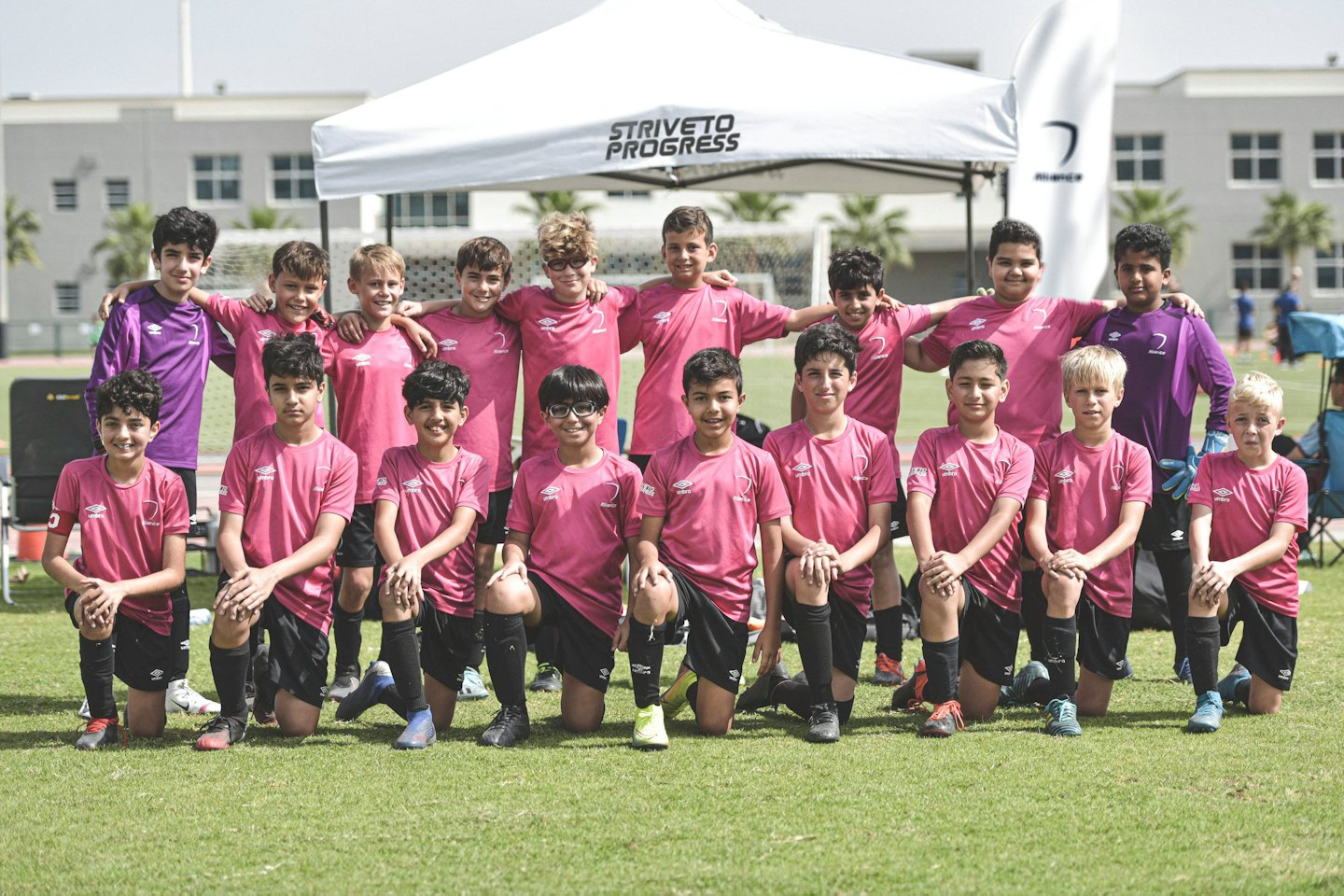 Junge Fußballspieler in Trikots posieren auf einem grünen Feld.